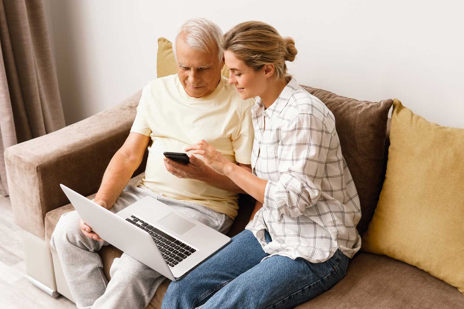 An adult daughter sitting with her father at home, going through paperwork together